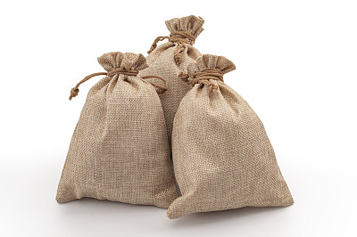 农业粗布麻袋，粗麻袋材料和亚麻面料的纺织概念，用三个棕色粗麻袋或麻袋堆在白色背景上孤立，并有剪路切口