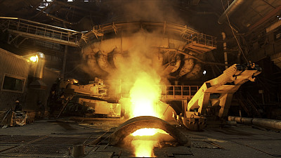 电炉炼钢车间，炎热黑暗，燃烧着火和烟。资料片。冶金厂生产钢水。