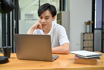 放松和休闲的亚洲男性大学生或男性办公室职员使用笔记本电脑
