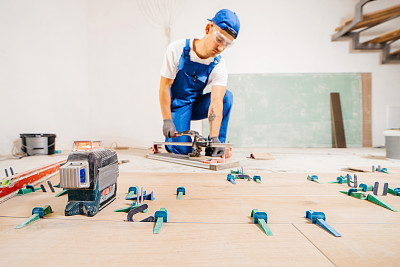 修理工的手在地板上的瓷砖切割机上切割瓷砖。近距离