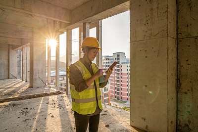 一位亚洲女建筑工人正在工地上使用手机