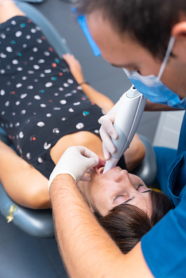 牙科诊所，牙医对躺着的病人进行3d扫描