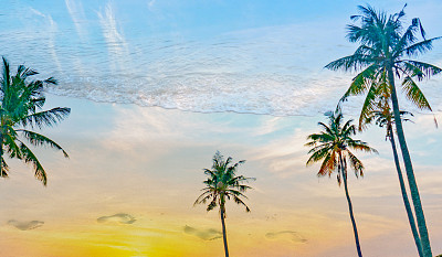 沙滩上的脚印和棕榈树的剪影。双重曝光图像