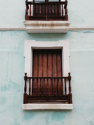 垂直拍摄的木质阳台和浅蓝色墙壁上的百叶窗。