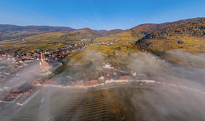 德瓦乔镇的Weisenkirchen的空中全景图和多瑙河上空雾蒙蒙的秋日清晨的葡萄园。瓦山谷,奥地利