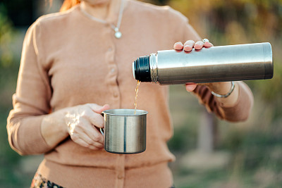 一个成熟女人的手从保温杯倒茶的特写