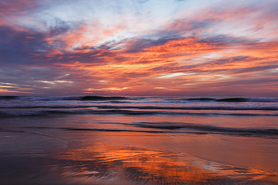 亮粉色和金色的落日在海洋地平线上的动态模糊反射