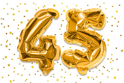 气球的数字由金箔制成，数字45在白色的背景上有亮片。有题词的生日贺卡。周年的概念。