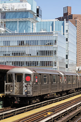 列车驶近皇后区高架地铁站，纽约市摩天大楼