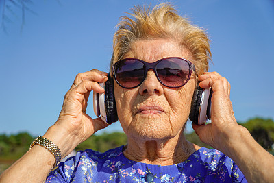 老妇人戴着耳机听音乐。职业疗法。老年人与科技