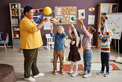 幼儿园的成熟老师和一群小朋友的行星模型
