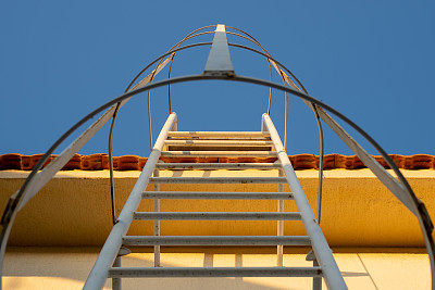 白色的金属梯子通向屋顶。铁防火梯。