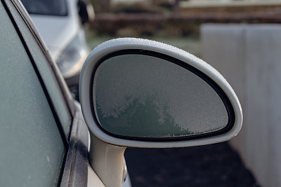 一辆停在室外停车场的汽车后视镜结冰，初冬结霜