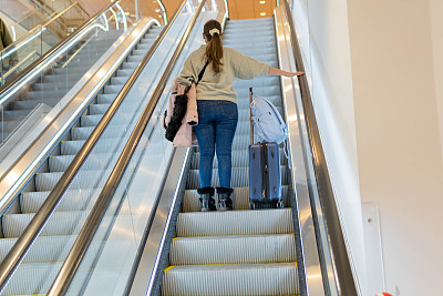 女旅客在机场乘坐自动扶梯