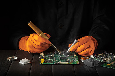 电子制造服务，电子板手工焊接。工头在车间里修理电脑或电子设备。