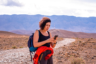 一名独自旅行的成年女子担心地看着自己的手机，因为她掉了手机套或收到了坏消息。越来越多的人选择独自旅行，有一个好的手机套是独自旅行和安全必不可少的