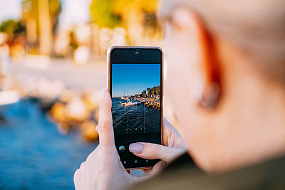 一名女子用智能手机拍摄风景照片