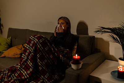 在电力危机和停电期间，一个生病的女人在黑暗的卧室里感到寒冷。