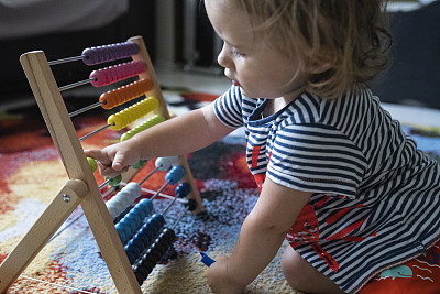 宝宝在家里玩彩色的木制算盘玩具。