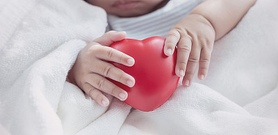 Asian newborn baby holding red heart shape squeeze balloon toy, Closeup hand of asian newborn baby with copy space background banner family parents love motherâs day bonding concept banner