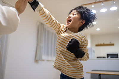 一个日本男孩在家里和他的妈妈一起做体操——跳