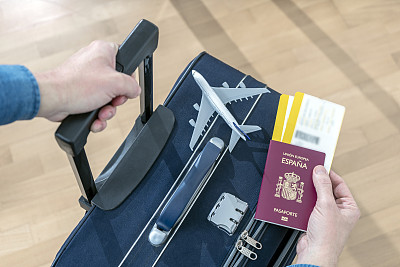 乘客持有西班牙护照，两张登机牌和一个手提箱在机场准备起飞。西班牙商务和度假旅行保险。