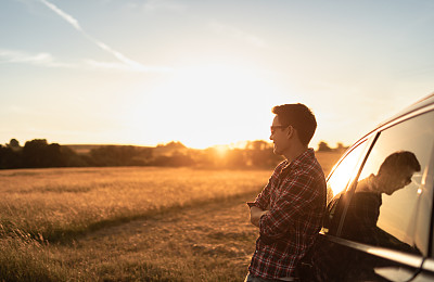 年轻英俊的男子休息，从车外看日落。