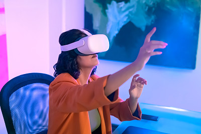 女商人在办公室戴着头戴式耳机享受VR体验
