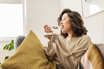 年轻的女人正坐在客厅里，享受着蛋糕