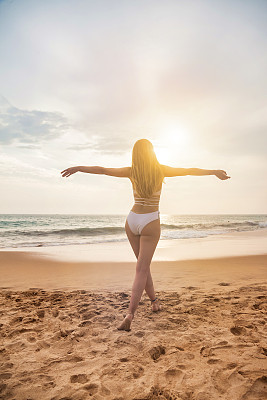 后视图年轻女子在白色泳装走一步与手一边在海洋背景，夏天。在热带海上享受轻松愉快的假期。旅游度假度假概念。复制文本空格