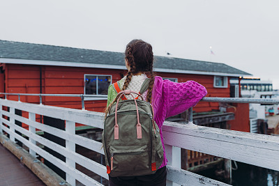 女性旅行者探索加州蒙特雷市渔人码头的后视图