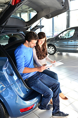 一对年轻夫妇在一家汽车经销商的展厅里购买和测试汽车