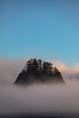 美丽强大的独立岩石功能，树木从大雾蓝天中冒出来