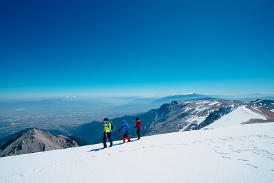 登山队一边走在山顶上，一边欣赏着森林和山脉的美景。