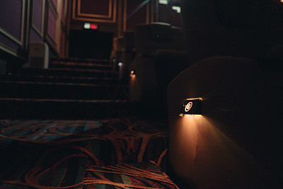 空荡荡的电影院的楼梯和过道。漆黑的电影院，只有亮的标志和红色的阶梯灯。