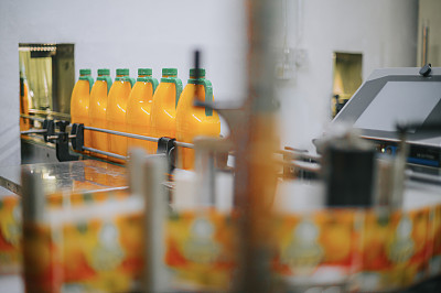 橙汁厂生产线装瓶生产线在终点线连续移动排队进行贴标包装