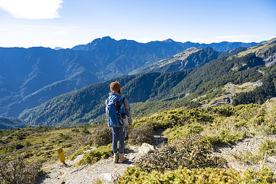 徒步旅行者站在山顶上看风景。