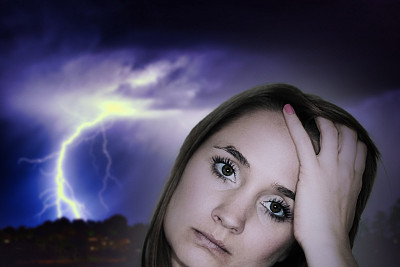 女人不高兴地抱着她的头，沮丧或头痛，面对着雷暴和闪电