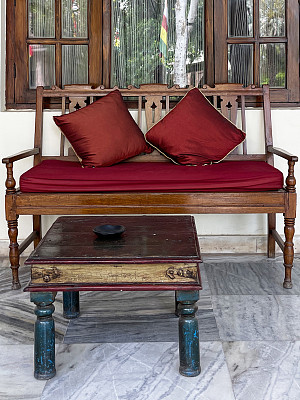 华丽的形象，木质长凳与红色软垫座位在窗前，沙发座位与两个红色方形垫子，咖啡桌，瓷砖地板，重点在前景
