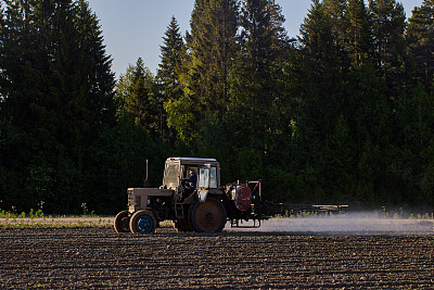 农用拖拉机在吊杆上用喷雾器给马铃薯作物施用除草剂。