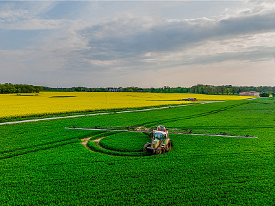 麦田拖拉机与施肥机鸟瞰图。带喷雾器的拖拉机鸟瞰图。在田间施用水溶性肥料、农药或除草剂。