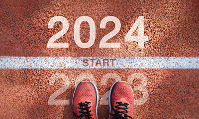 新的一年2024概念，成功的开始。文字2024写在柏油路上，男跑步者准备迎接新的一年。对挑战或职业道路和改变的概念。