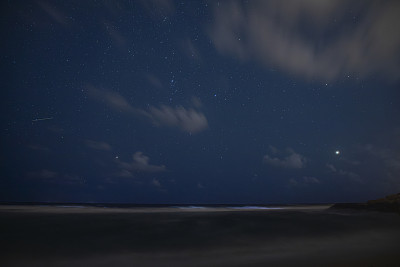 繁星点点的天空和夜晚海滩上的木星