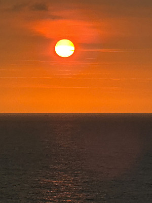 太阳在海上地平线上的橙色天空中落下的图像