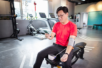 中年男子在健身房用电子血压计测量血压