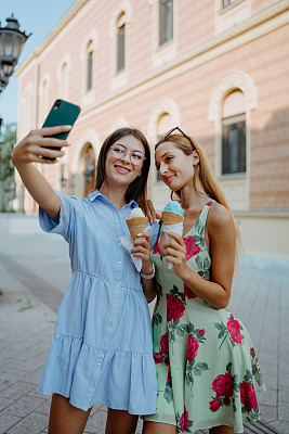 两个朋友喜欢吃冰淇淋，用一张城市自拍记录他们的一天