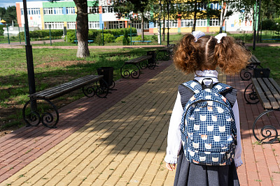 学生背着书包，穿着校服，在学校操场上回到画框里。9月1日返校。一个快乐的学生。小学教育，小学课堂。人生之路，通往知识之路