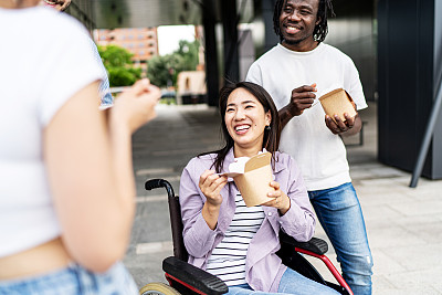 坐在轮椅上的年轻女子在户外和她的朋友们有说有笑