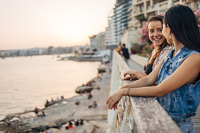 两个朋友站在海上的码头上，享受着马耳他首都的美景，玩得很开心