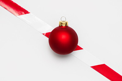 冠状病毒2019-nCoV期间2021年新年和圣诞节的概念。红球和禁止带在浅色背景上平铺顶视图。呆在家里。假期隔离。禁止假日